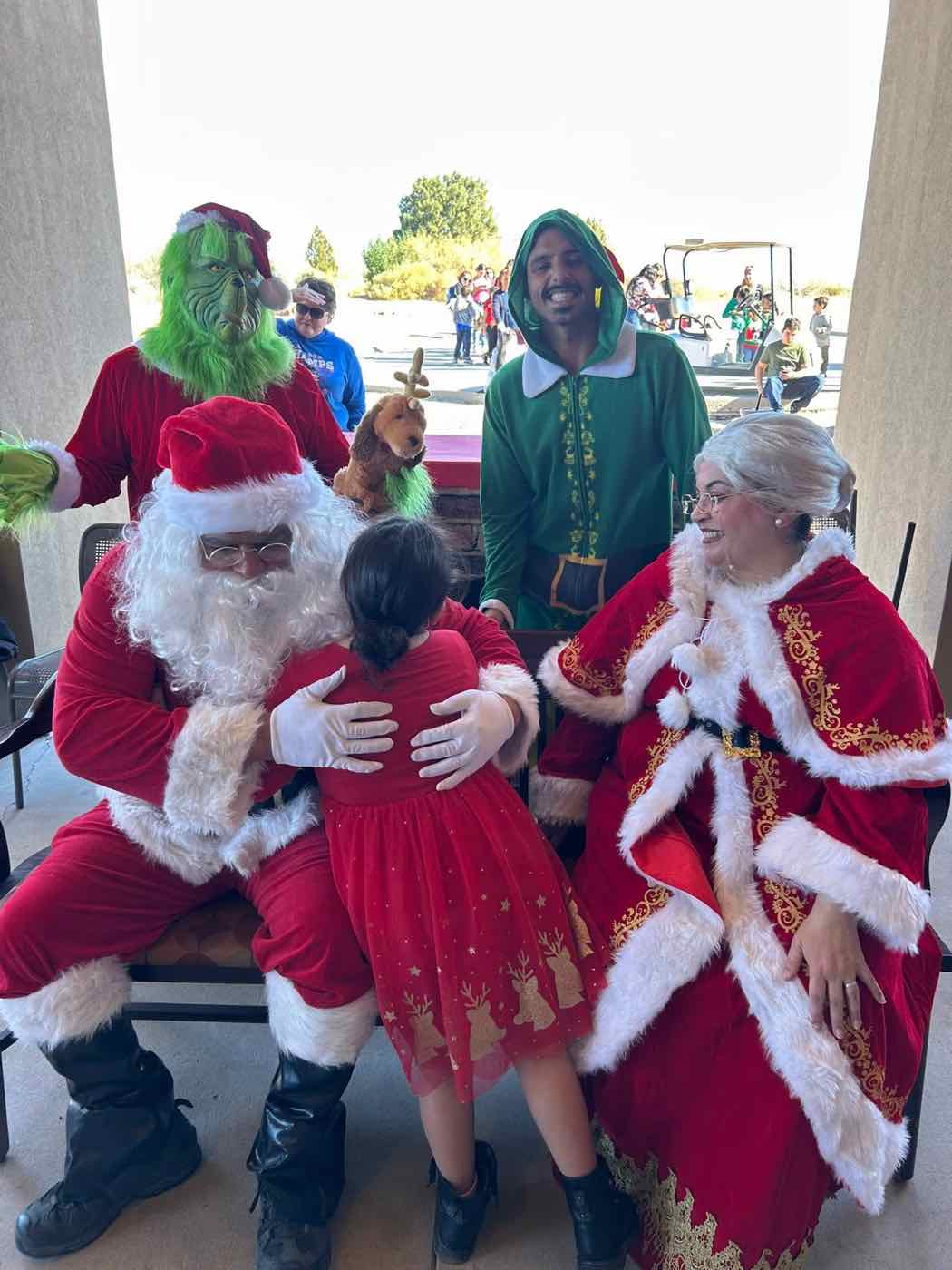 A child hugging Santa, with Mrs. Claus, an elf and the Grinch at a past Reach for a Star Christmas party