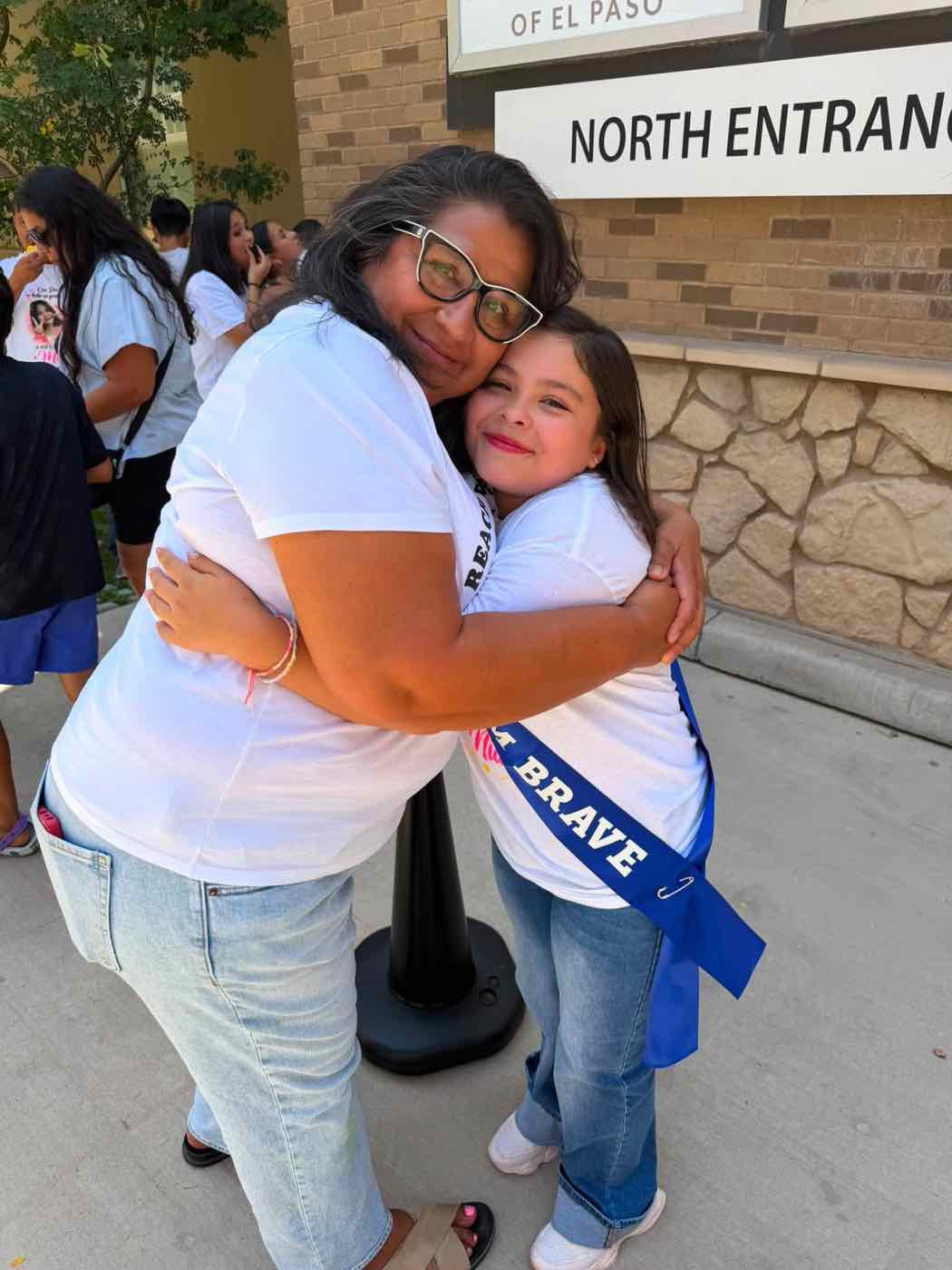 A Reach for a Star supporter hugging a smiling girl wearing a sash