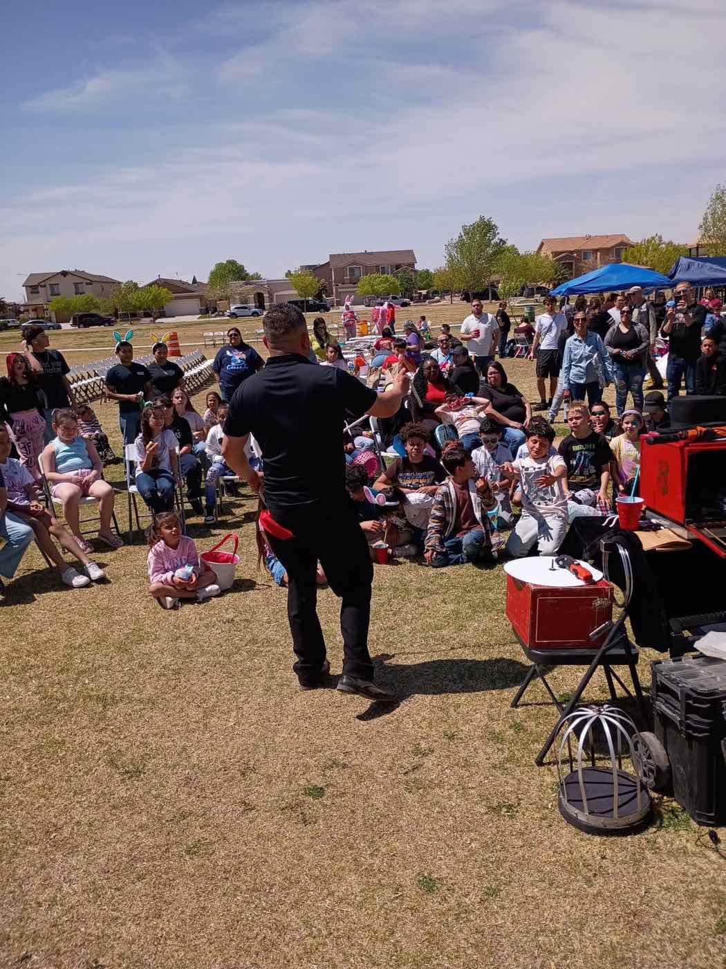 A magician performing for a crowd of kids and families at the Reach for a Star Easter party