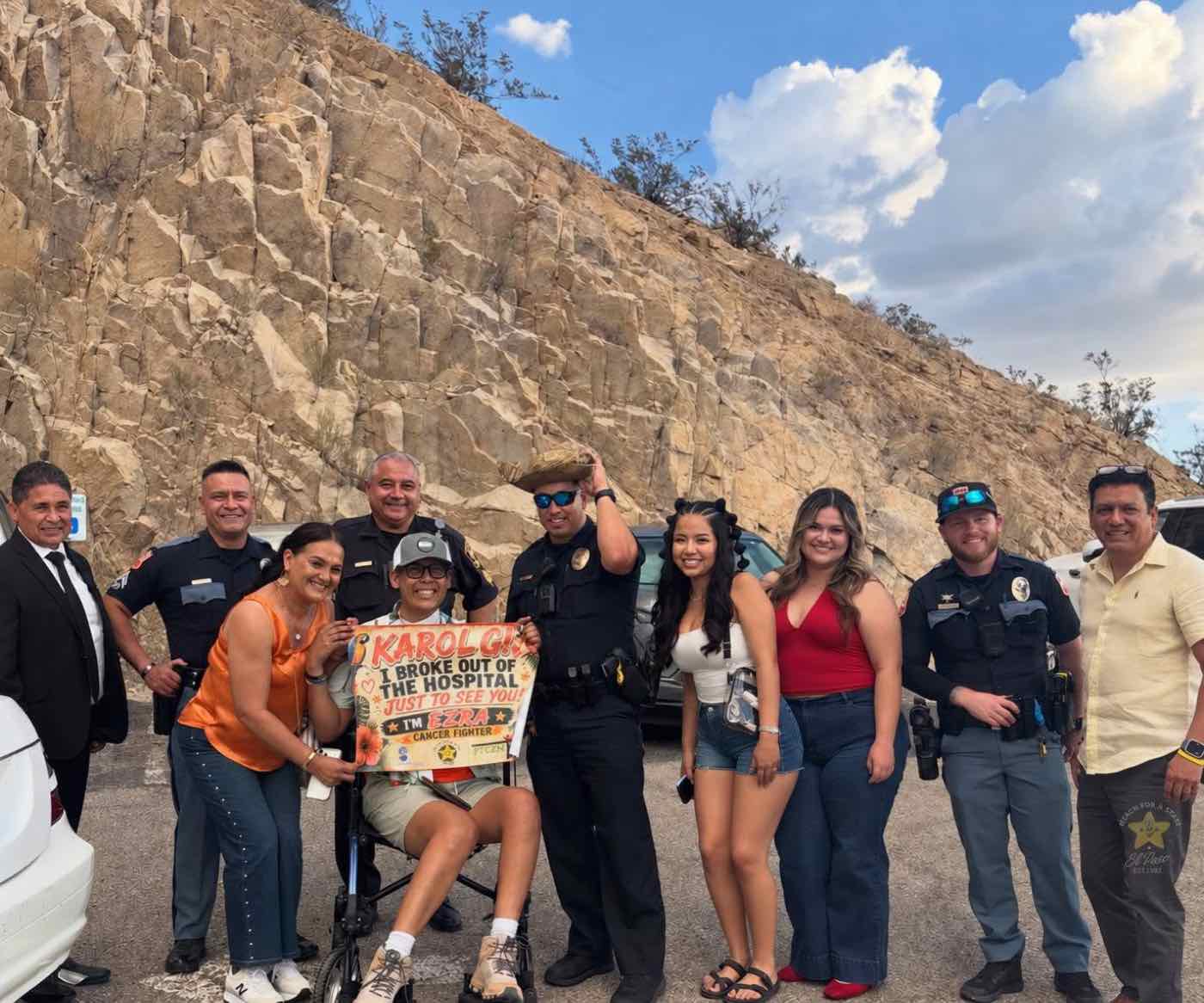 A wish recipient holding a sign for Karol G, surrounded by police officers and supporters