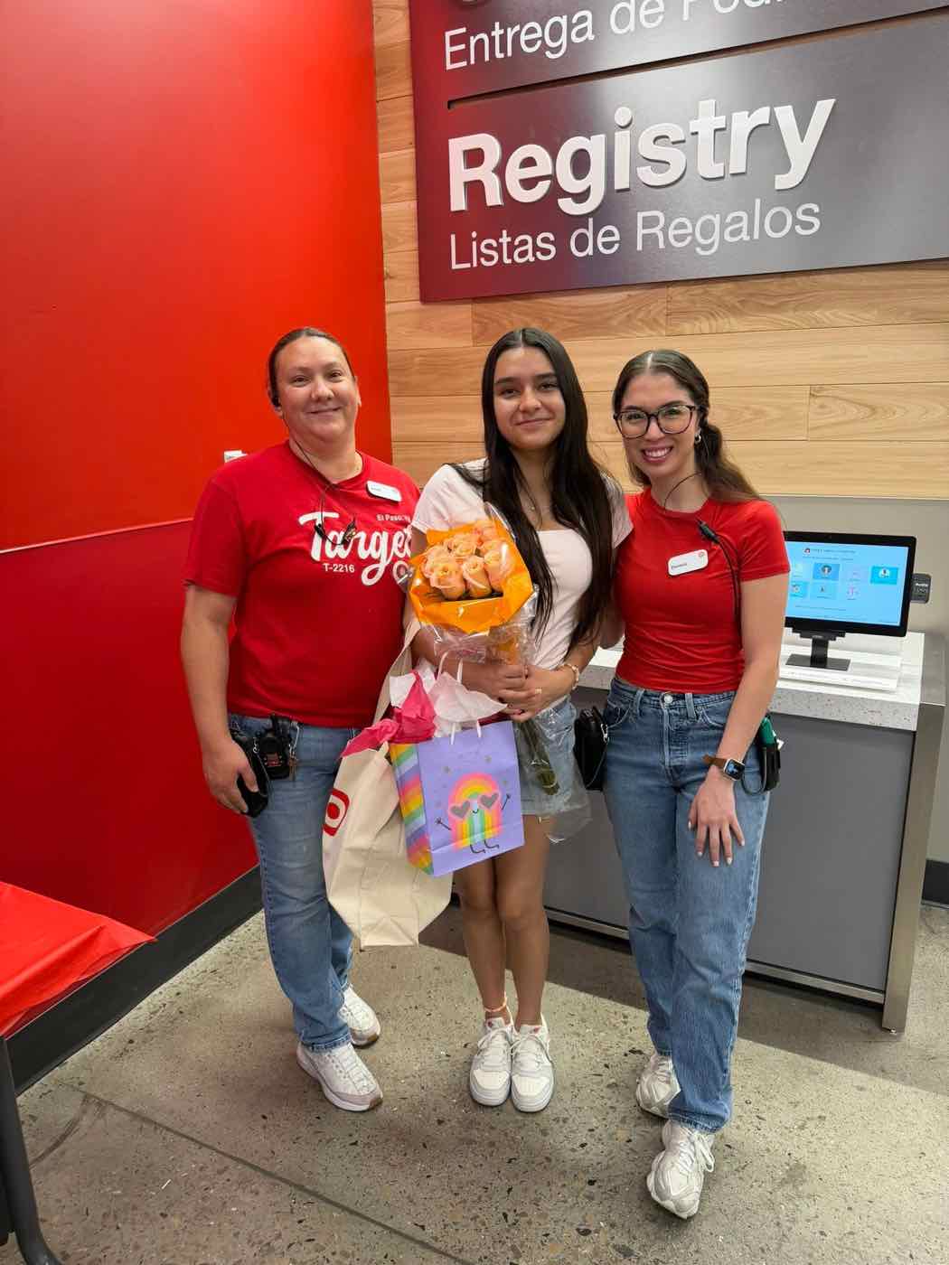 A teen holding a bouquet and gifts, with two Target team members